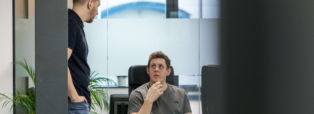 Two men looking at each other discussing work.