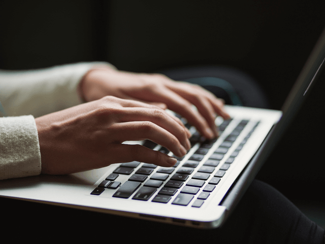 Hands are shown typing on a laptop keyboard.